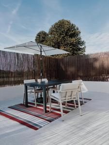 a table and two chairs and an umbrella on a rug at Charmant T2 - 4 couchages à 15mn de la mer in Merlevenez +2 photos