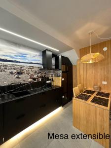 a kitchen with black cabinets and a view of a beach at Suite Playa in Miño