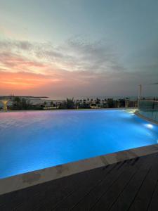 a large blue swimming pool with a sunset in the background at Beautiful Studio Retreat in Ras al Khaimah