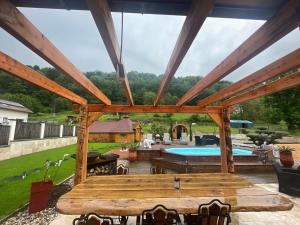 a patio with a wooden pergola and a swimming pool at KOTA bien être jaccuzzi , sauna , piscine chauffée , soins bien être in Voissant +22 photos