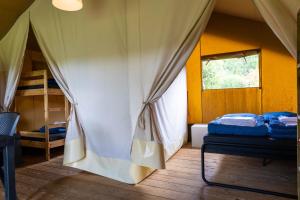 a room with a tent with two beds and a window at Safaritent bij speeltuin voor gezinnen op groen rustig park op de Veluwe in Epe