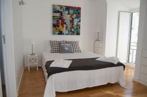 a white bedroom with a bed and a painting on the wall at Casa do Chafariz in Cascais