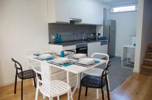 a white dining room table with chairs and a kitchen at Casa do Chafariz in Cascais