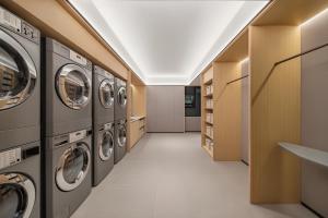 a laundry room with a row of washers and dryers at Ji Hotel Phnom Penh Downtown in Phnom Penh