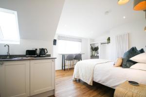 a white bedroom with a bed and a kitchen at Abode Above at Tor View in Padstow