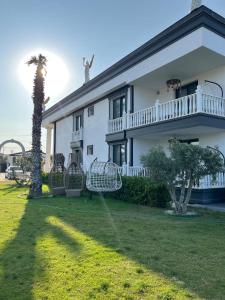 a white house with a palm tree in the yard at Apera Garden in Sancaklı