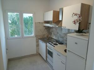 a kitchen with white appliances and two windows at Villa BORIĆ DARKO in Podgora