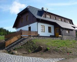 a large wooden house with a gambrel roof at Apartmány Na Kobylce in Modrava