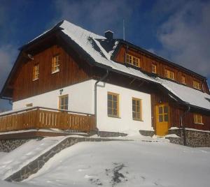 a house with snow on the ground in front of it at Apartmány Na Kobylce in Modrava