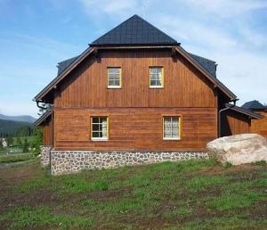 a large wooden house with a black roof at Apartmány Na Kobylce in Modrava