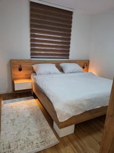a bedroom with a large bed with a wooden headboard at Apartman Adria Lux Doboj in Doboj