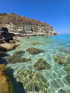 a group of people swimming in the ocean with rocks at Almarea Apartments in Santa Domenica