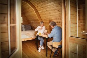 a man and woman sitting at a table in a cabin at Camping De Bosrand in Sint Geertruid