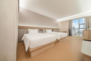 two beds in a hotel room with a large window at Ji Hotel Phnom Penh Downtown in Phnom Penh +49 photos