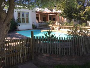 a fence around a swimming pool in front of a house at Classic Home in Franschhoek in Franschhoek