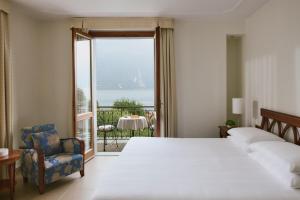 a bedroom with a bed and a chair and a large window at Belvedere Bellagio in Bellagio
