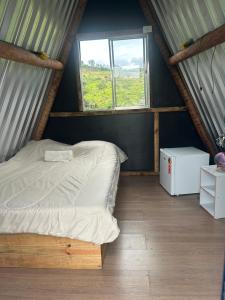 a bed in a room with a window at Bangalô Cachoeira Bem Vinda in Itabirito