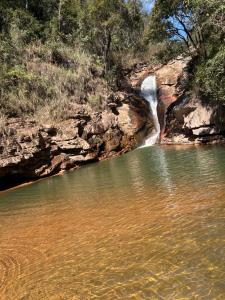 a waterfall in front of a body of water at Bangalô Cachoeira Bem Vinda in Itabirito