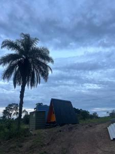a palm tree next to a building and a tent at Bangalô Cachoeira Bem Vinda in Itabirito