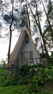 a small house with a triangular roof in the woods at The Nest Park in Prigen