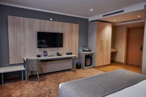 a bedroom with a bed and a desk with a television at Grand Altyn Hotel in Shymkent