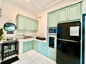 a kitchen with green cabinets and a black refrigerator at Suite Room The Megatruh in Kejayan