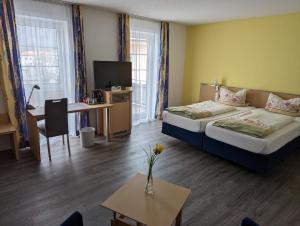 a hotel room with two beds and a desk and a table at Steakhüsli Hotel- Restaurant in Schopfheim