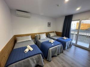 three beds in a room with blue sheets at Malva Hostel Estartit in L'Estartit