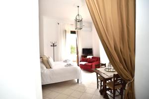 a living room with a bed and a red chair at VILLA La Pineta di Sinalunga, vicino a Montepulciano e Val D'Orcia in Sinalunga