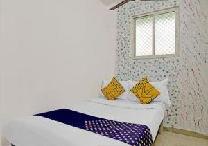 a bedroom with a bed with yellow and blue pillows at HOTEL Sarovar in Ahmedabad