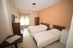 a hotel room with two beds and a television at Hotel Galaxias in Kato Loutraki