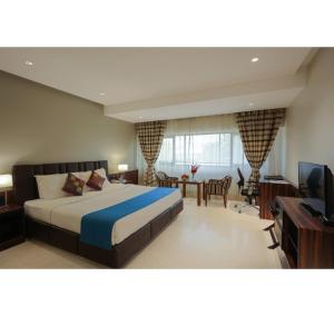 a bedroom with a bed and a desk and a television at Hotel Prince, Bhuj in Bhuj