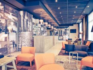 a waiting room with orange chairs and tables at Mercure Saint Malo Balmoral in Saint Malo