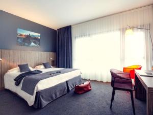 a hotel room with a large bed and a desk at Mercure Saint Malo Balmoral in Saint Malo +109 photos