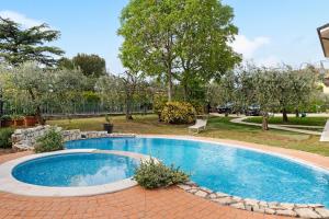 a swimming pool in a yard with a bench and trees at Casa Alessandra in Torri del Benaco