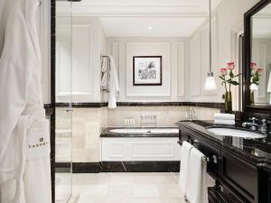 a white bathroom with a sink and a tub at The Langham London in London