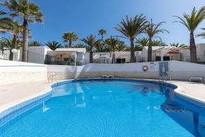 a swimming pool with palm trees in the background at Heiwa Apartment With Pool in Costa Calma