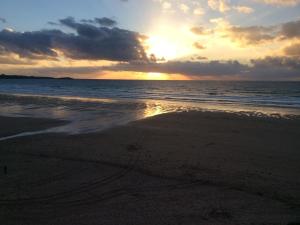 a sunset on a beach with the ocean at Lower Barns Boutique B&B in St Austell