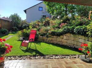 a red chair sitting in a yard next to a stone wall at Ferienwohnung Klaus in Ebermannstadt +35 photos