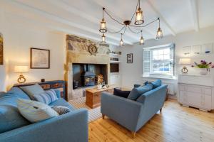 a living room with two blue couches and a fireplace at The Old Ale House in Craster