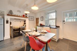 a kitchen with a table and red chairs in a room at The Old Ale House in Craster