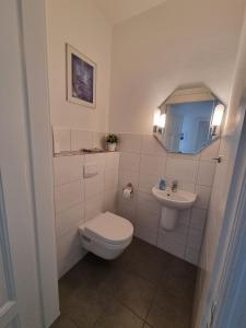 a white bathroom with a toilet and a sink at Ferienwohnung Biethahn - Gaarden in Groß Brodersby +4 photos