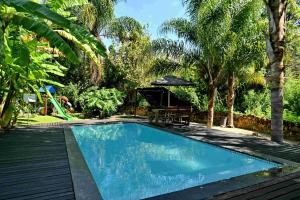 a swimming pool in a backyard with a picnic table and trees at BON Hotel Rustenburg in Rustenburg