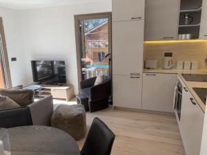 a kitchen with white cabinets and a living room at Dents Blanches B103 by Avecoeur in Morzine