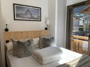 a bed with pillows and a picture on the wall at Dents Blanches B103 by Avecoeur in Morzine