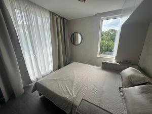 a bedroom with a white bed and a window at Апартамент АТЕА in Kavarna