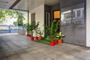 a lobby with a bunch of plants in red pots at Hotel Orchard in Pune