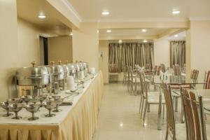 a restaurant with a row of tables and chairs at Hotel Orchard in Pune