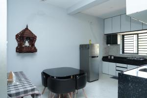 a kitchen with a black table and a refrigerator at Sukruthi service apartment 3BHK in Mangalore