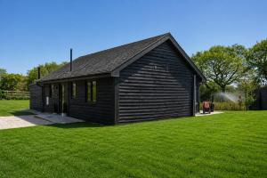 a small black building in a field of grass at Holly Tree Luxury Lodge in Skipwith